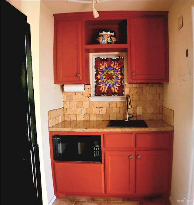 bar with black microwave, decorative backsplash, and a sink