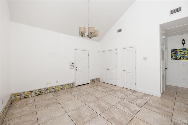 foyer entrance with a notable chandelier, light tile patterned floors, and high vaulted ceiling