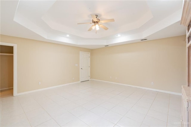 tiled spare room with a raised ceiling and ceiling fan