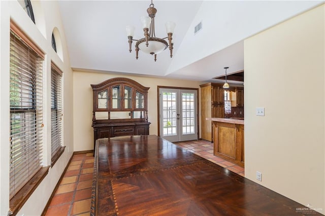 dining room with lofted ceiling, french doors, and an inviting chandelier