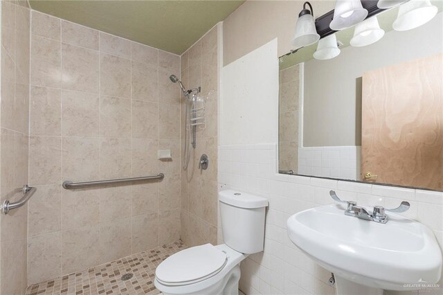 2915 Roselawn Dr, Weslaco, TX 78596 - bathroom featuring a tile shower, wainscoting, and tile walls