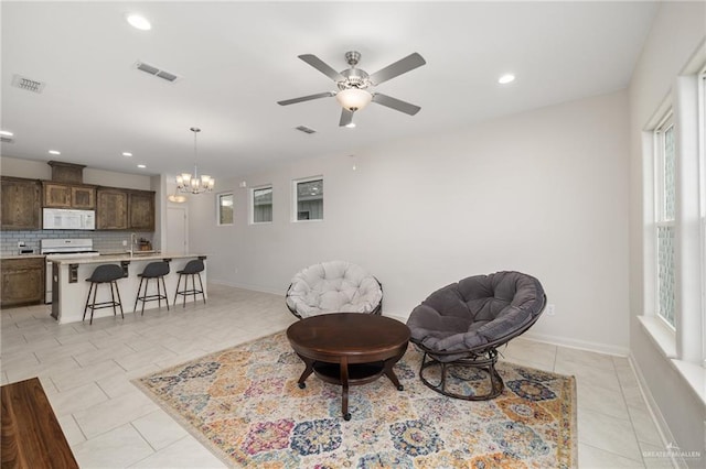 living area featuring light tile patterned floors and ceiling fan with notable chandelier