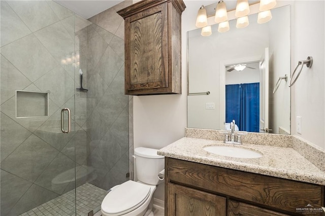 bathroom with vanity, toilet, ceiling fan, and a shower with shower door