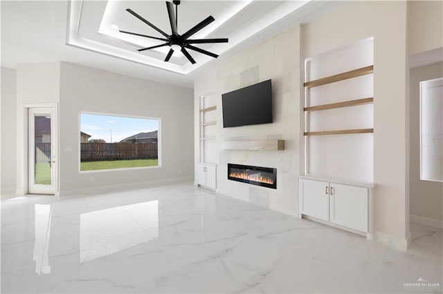 unfurnished living room featuring built in features, ceiling fan, and a tray ceiling