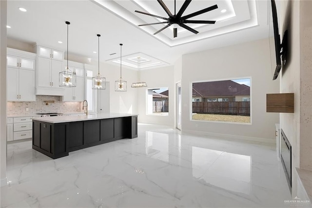 kitchen with a raised ceiling, white cabinetry, a large island, and pendant lighting