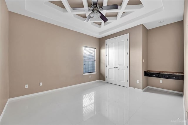 unfurnished bedroom featuring coffered ceiling, ceiling fan, light tile patterned floors, beam ceiling, and a closet