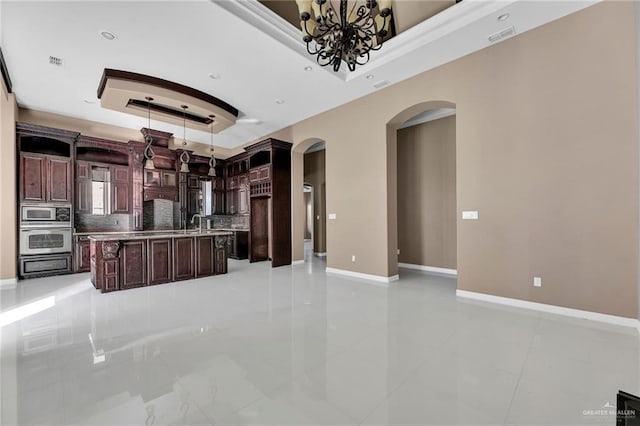 kitchen featuring tasteful backsplash, dark brown cabinets, stainless steel appliances, a raised ceiling, and hanging light fixtures