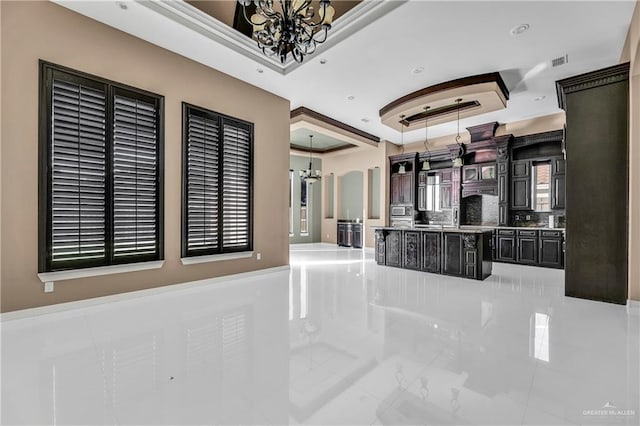 interior space with a raised ceiling, dark brown cabinetry, and a chandelier