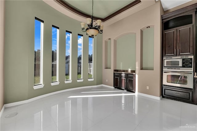 interior space featuring a raised ceiling, light tile patterned floors, and an inviting chandelier