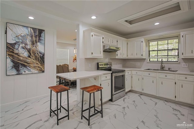 kitchen featuring decorative backsplash, sink, white cabinets, electric range, and a breakfast bar