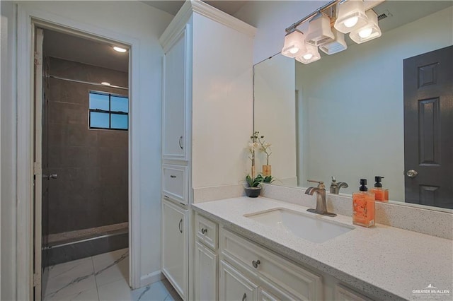 bathroom with tiled shower and vanity