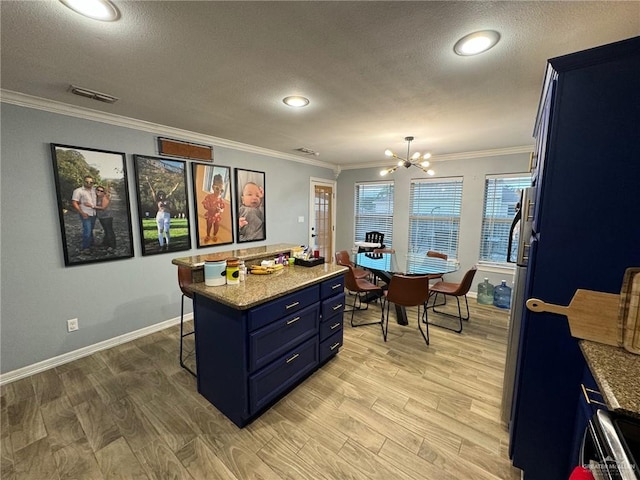 kitchen with light hardwood / wood-style floors, a center island, blue cabinets, and crown molding