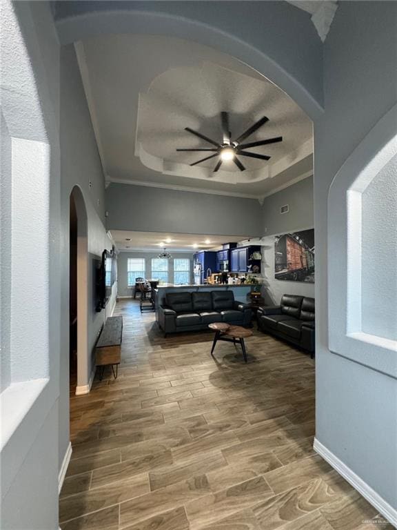 living room featuring a tray ceiling, ceiling fan, and hardwood / wood-style flooring