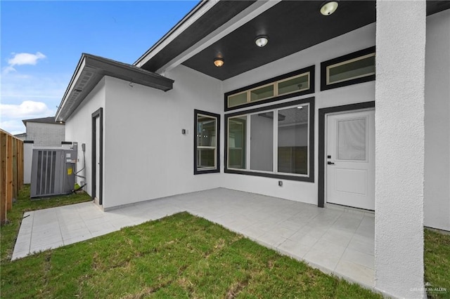 rear view of property with a lawn, a patio area, and central AC unit