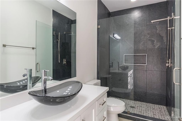 bathroom featuring toilet, a shower with door, and vanity