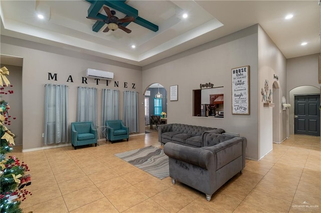 living room with ceiling fan, a raised ceiling, an AC wall unit, a towering ceiling, and light tile patterned floors