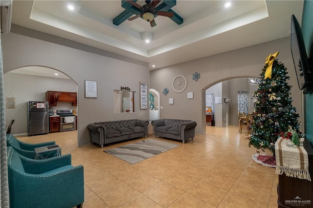 tiled living room featuring a tray ceiling and ceiling fan