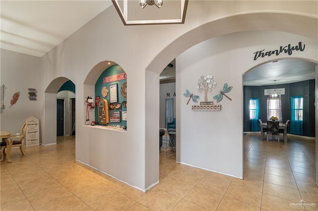 corridor with light tile patterned floors and a notable chandelier