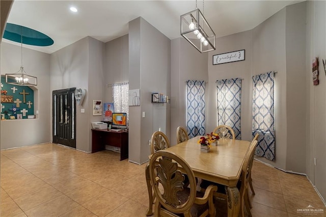 dining space featuring a healthy amount of sunlight, light tile patterned floors, a high ceiling, and an inviting chandelier