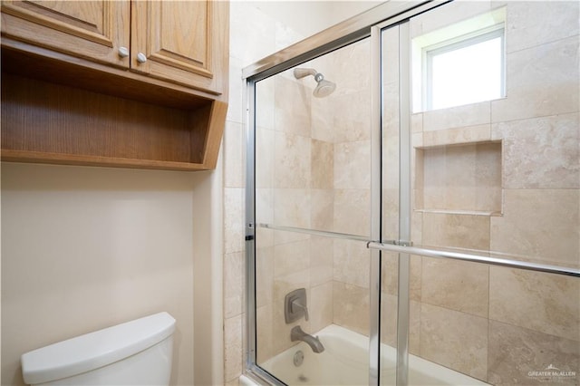 bathroom featuring toilet and bath / shower combo with glass door