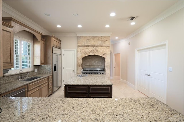 kitchen with light stone countertops, stainless steel appliances, sink, light tile patterned floors, and a center island