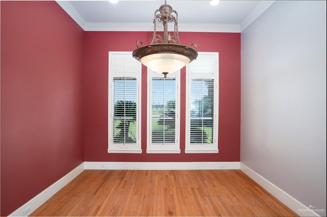 spare room featuring a chandelier, hardwood / wood-style flooring, and ornamental molding