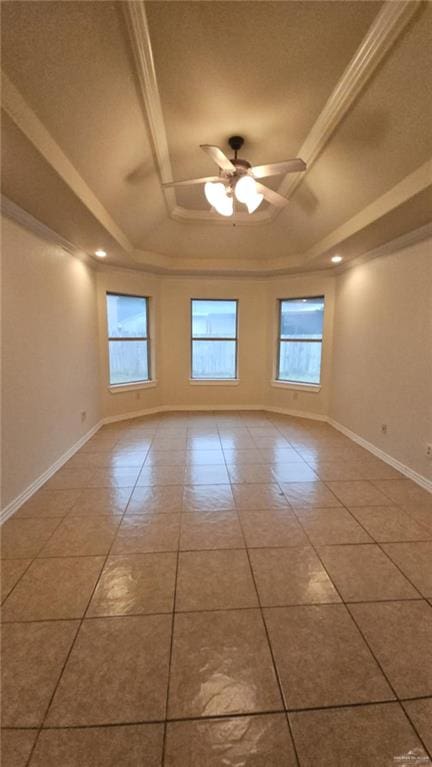 tiled spare room featuring ceiling fan, ornamental molding, and a tray ceiling