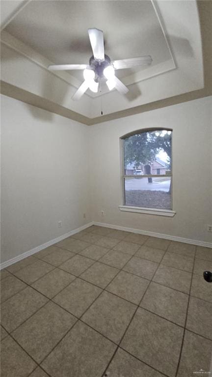 spare room with ceiling fan, tile patterned flooring, and a raised ceiling