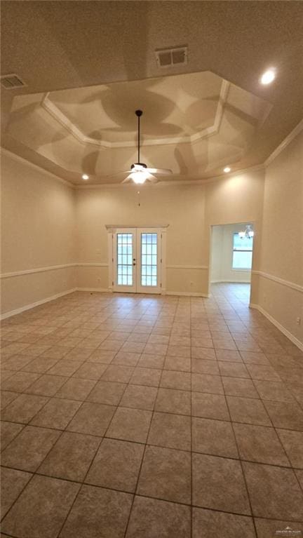 tiled spare room with a raised ceiling, ornamental molding, ceiling fan, and a healthy amount of sunlight