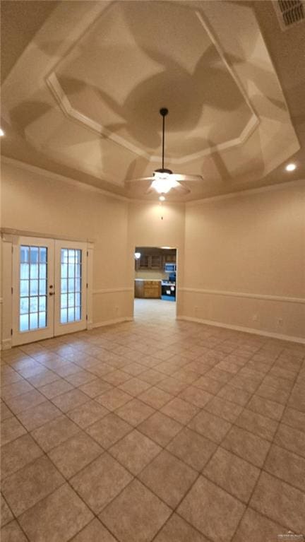 unfurnished room featuring tile patterned flooring, a towering ceiling, ceiling fan, french doors, and a tray ceiling