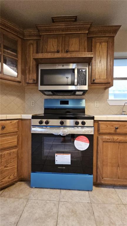 kitchen with decorative backsplash, light tile patterned floors, and appliances with stainless steel finishes