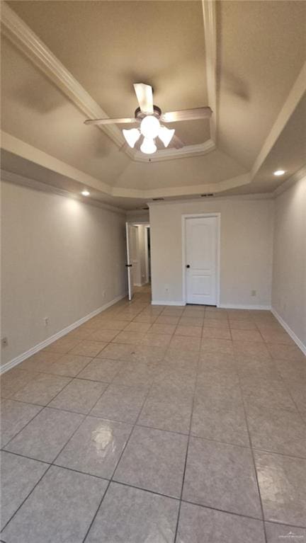 empty room with light tile patterned floors, a raised ceiling, ornamental molding, and ceiling fan