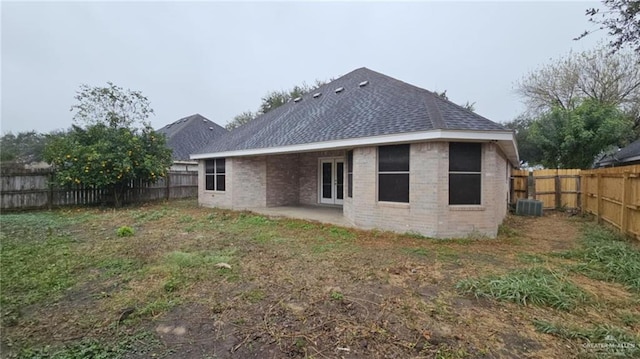 back of property with central air condition unit, a patio area, and a yard