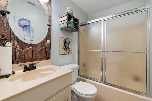 full bathroom with shower / bath combination with glass door, vanity, a textured ceiling, and toilet