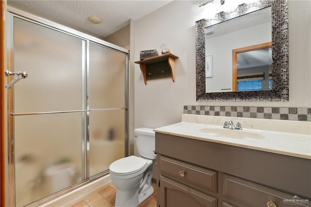 bathroom featuring vanity, tile patterned flooring, toilet, a textured ceiling, and walk in shower