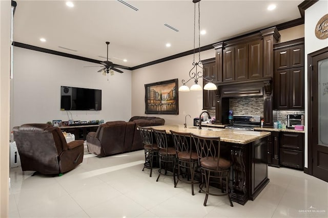 kitchen featuring black range oven, decorative light fixtures, a center island with sink, and dark brown cabinets