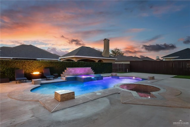 pool at dusk featuring an in ground hot tub, a gazebo, pool water feature, and a patio area