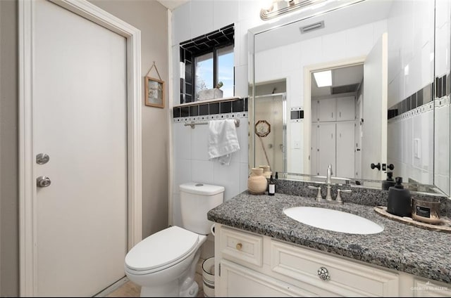 bathroom with toilet, tile walls, walk in shower, and vanity