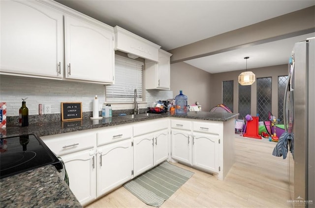 kitchen with white cabinetry, stainless steel fridge, kitchen peninsula, pendant lighting, and sink