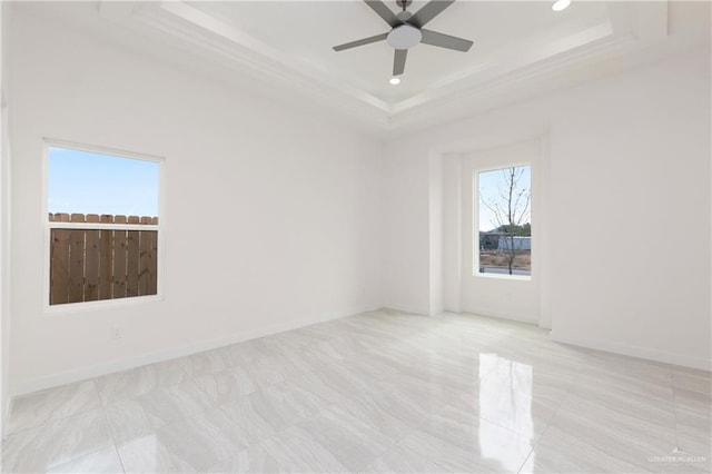 empty room featuring a raised ceiling and ceiling fan