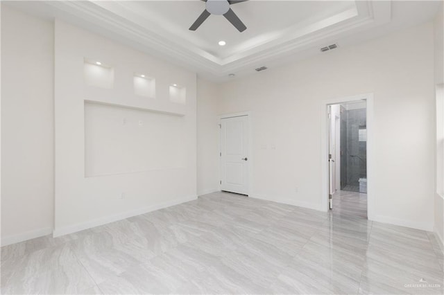 unfurnished room with ceiling fan, a raised ceiling, and a towering ceiling