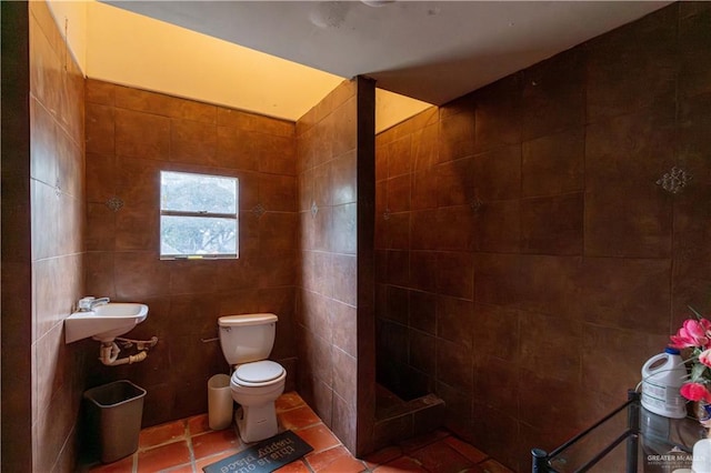 bathroom with tile patterned flooring, sink, toilet, and tile walls