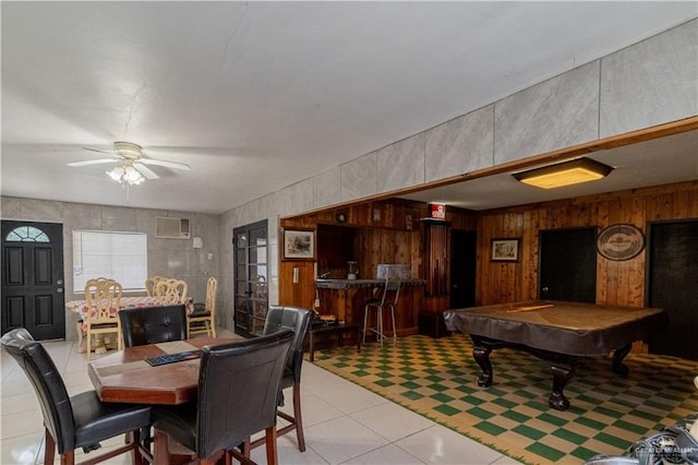 tiled dining area featuring wooden walls, ceiling fan, a wall mounted air conditioner, and billiards