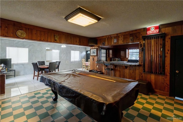 recreation room with a textured ceiling, wood walls, and billiards