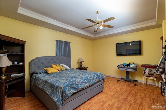 bedroom featuring hardwood / wood-style flooring, ceiling fan, and a tray ceiling