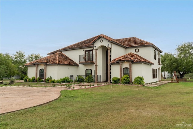 mediterranean / spanish home with a balcony and a front lawn