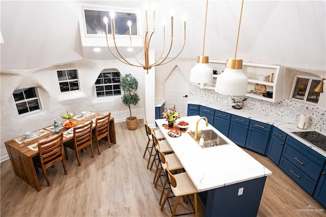 420 N Mayberry Rd, Alton, TX 78573 - kitchen with blue cabinets, a kitchen breakfast bar, light wood-type flooring, black electric stovetop, and a center island with sink