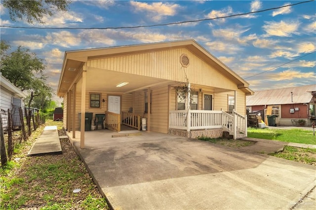 view of front of property featuring driveway, covered porch, fence, and an attached carport