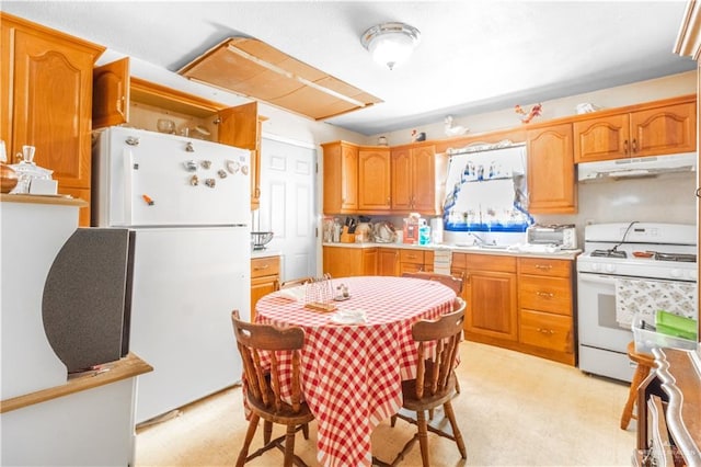 kitchen featuring white appliances, light floors, light countertops, under cabinet range hood, and a sink