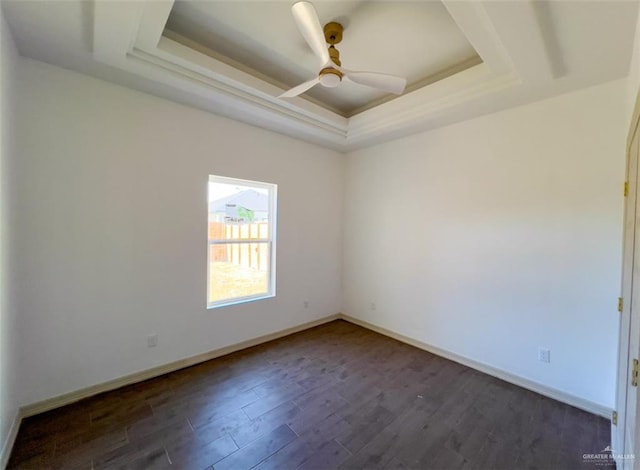 spare room with dark wood-type flooring, a raised ceiling, and ceiling fan